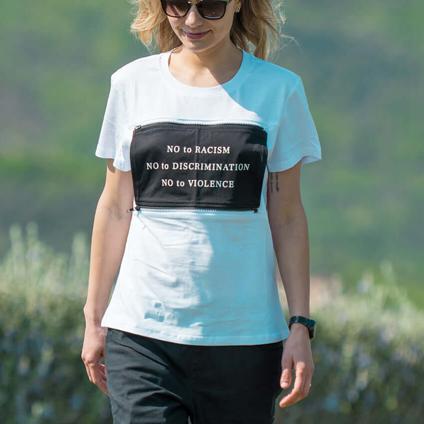The woman wears the white MULTI shirt con NO RACISM patch