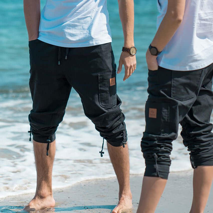 two people standing on the beach next to the water, wearing DOWNUnders