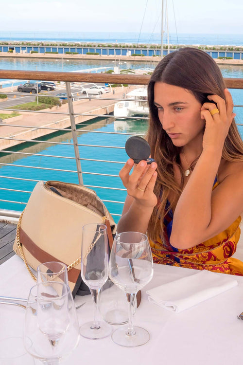 Woman on terrace with beige convertible handbag