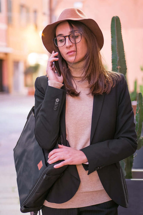 Woman talking on the phone with black convertible backpack on her shoulder