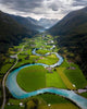 bird view of a green valley between the mountains with the blue river running through